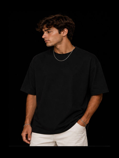 Man wearing a black t-shirt and white pants against a black background